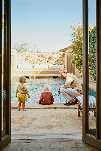 Padre con sus hijos junto a la piscina de casa